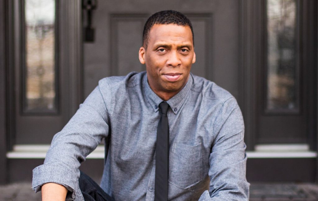 A photo of Ken sitting on the steps of his home.