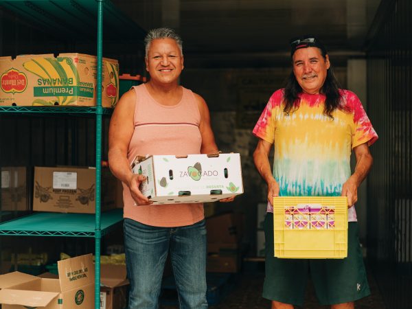 Two men holding groceries to give to people in need